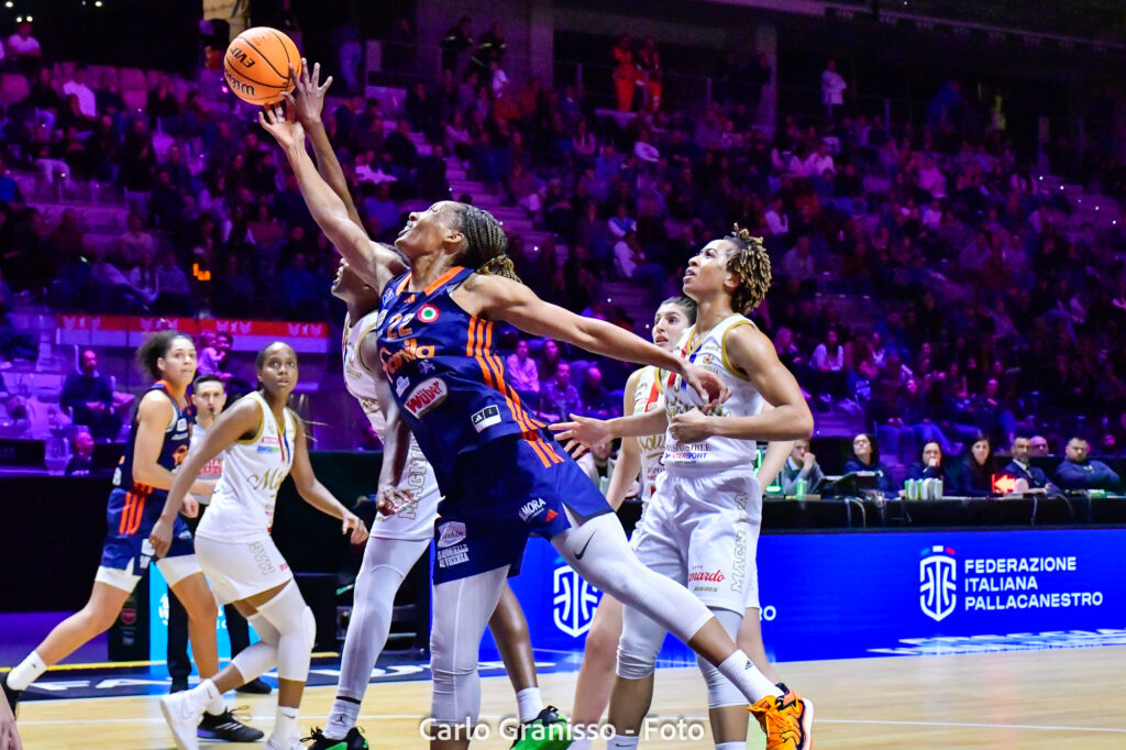 Andrè Olbis Futo di Schio in maglia blu numero 22 si allunga in aria per un layup in acrobazia, circondata dalla difesa di Campobasso in maglia bianca, durante la semifinale di Coppa Italia LBF.